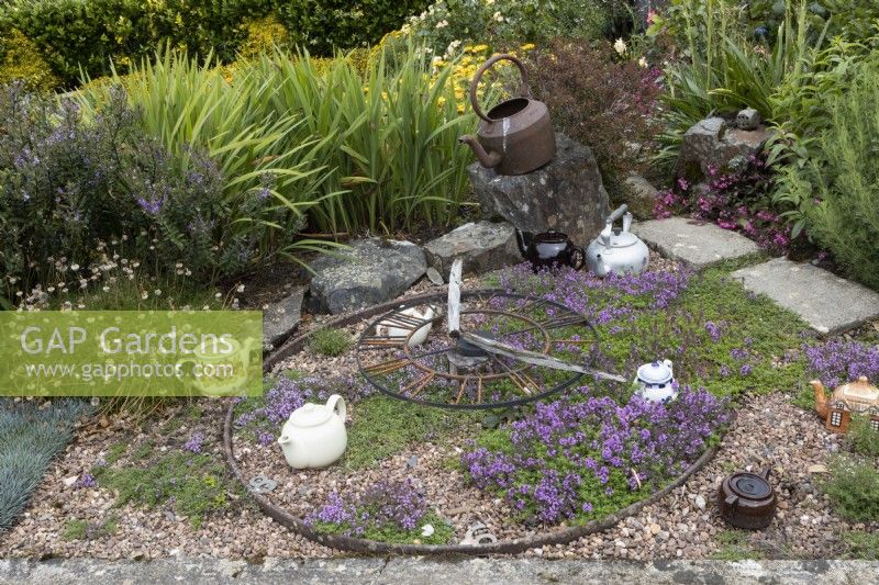 Thyme for Tea, an installation of teapots, kettle, a clock and thyme set amongst gravel. Harbour Lights, Devon NGS garden. July. 