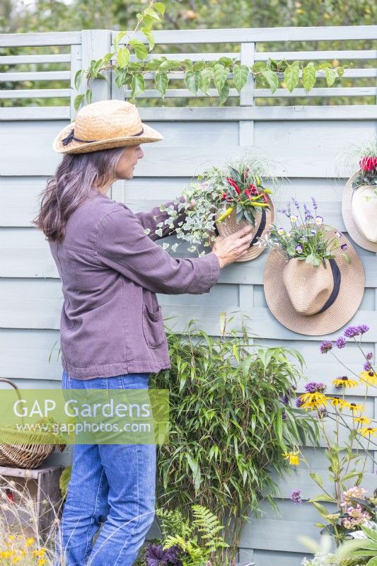 Woman hanging hat planters on wooden fence