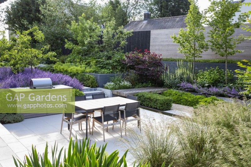 Outdoor dining and barbecue area on terrace of modern garden