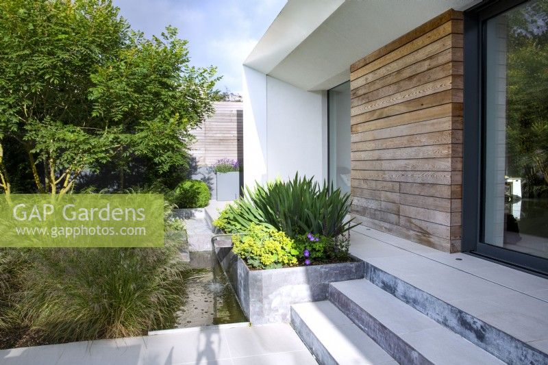 Metal raised bed and water feature outside contemporary house