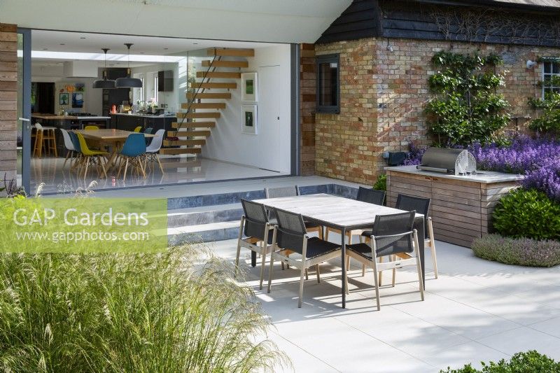 Outdoor dining area with view into modern kitchen-diner 
