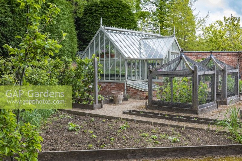 A formal kitchen garden with espaliered fruit trees, bespoke oak cloches to protect vulnerable crops, and an Alitex greenhouse.