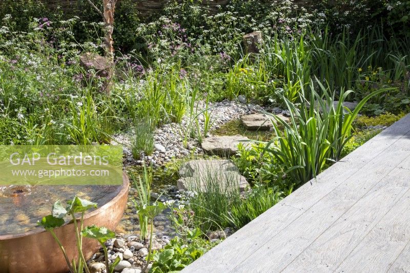Composite decking board next to a stream and metal copper container water feature
