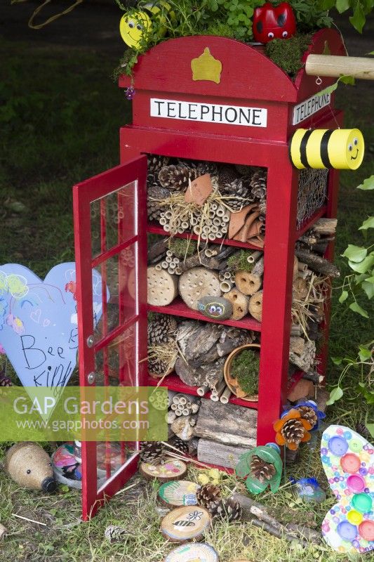 An insect hotel made by children from a model red telephone box