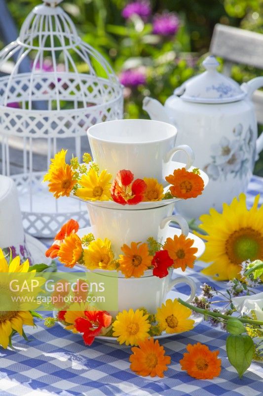 Pot marigolds and nasturtiums on a stand made of teacups and saucers.