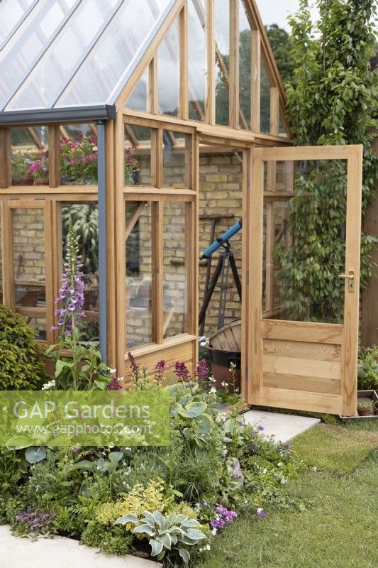 Wooden glasshouse with perennial bed, June