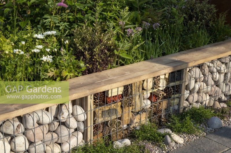 A gabion frame insect hotel with a reclaimed timber bench