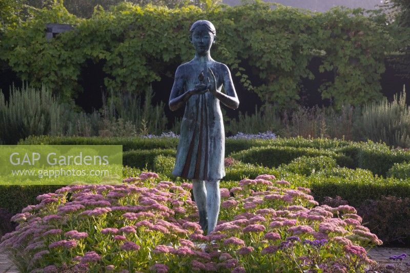 The Lamp of Wisdom statue surrounded by Sedum 'Autumn Joy', and box topiary in the formal garden at Waterperry Gardens
