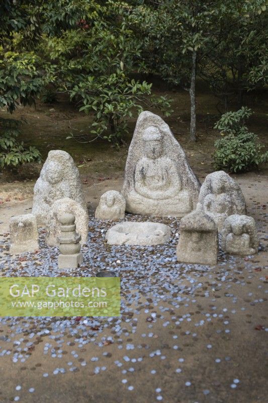 Group of stone Buddhas with coins on ground as offerings. 