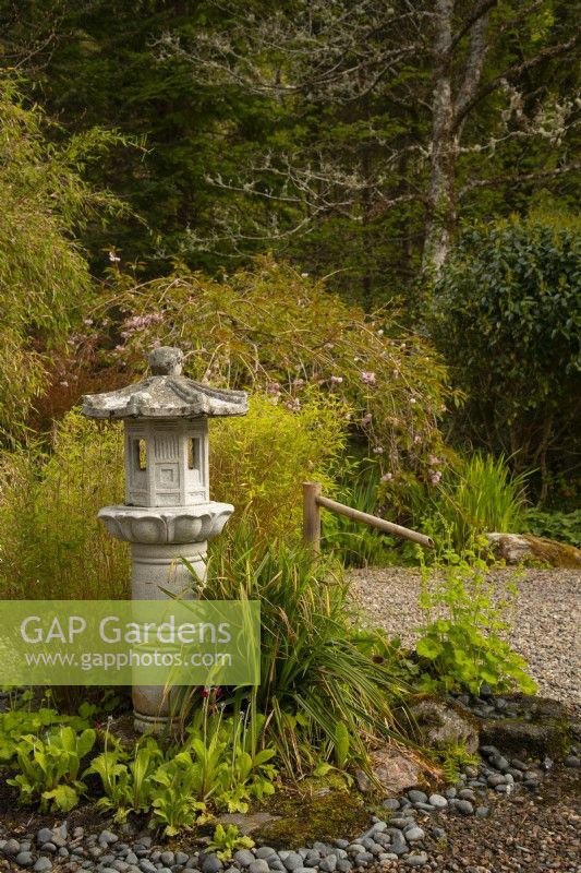 A carved stone Japanese lantern and Japanese bamboo water fountain in the Japanese garden.