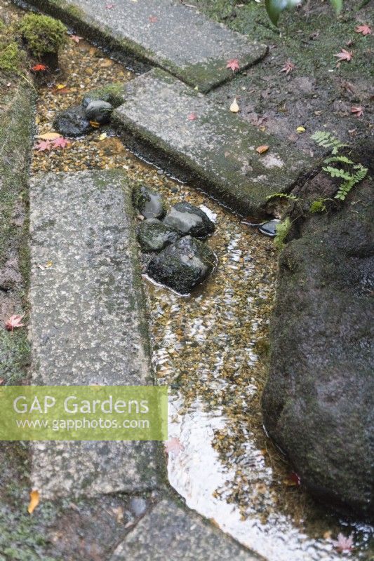 Rill of water between stone slab stepping stones.