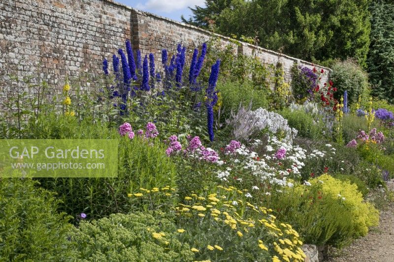 Mixed border against a brick wall at Waterperry Gardens, July