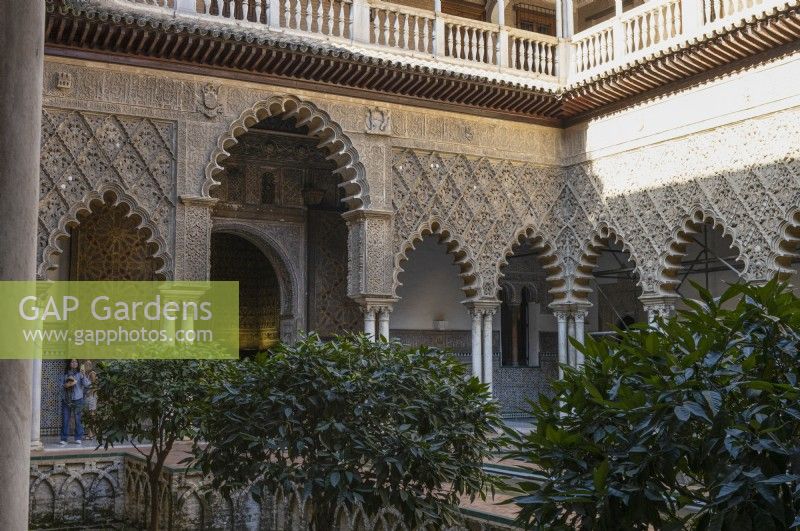 The Patio de las Doncellas, Maidens Courtyard, with poly lobed arches and architecture in the Mudejar style with standard fruit trees. Real Alcazar Palace gardens, Seville. Spain. September. 