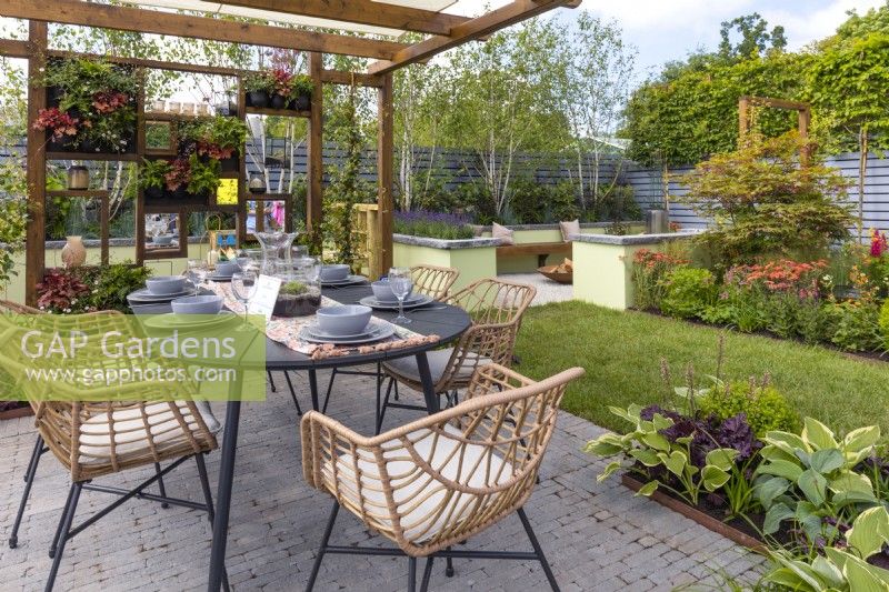 Small garden with a dining area, a relaxing area, a kid's area and colourful perennials beds. Boundary plantings consisting of tall Carpinus betulus pleached and Betula utilis var. jacquemontii provide privacy. June. Designer: Colm Carty, Bord Bia Bloom 2023 