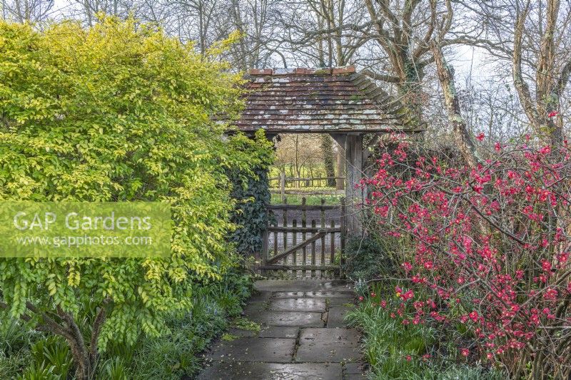 View through a covered lych gate garden entrance in early Spring - February
