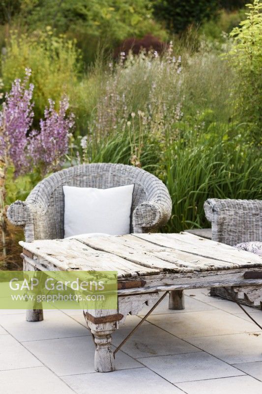 Old wooden table with wicker seating in a July garden