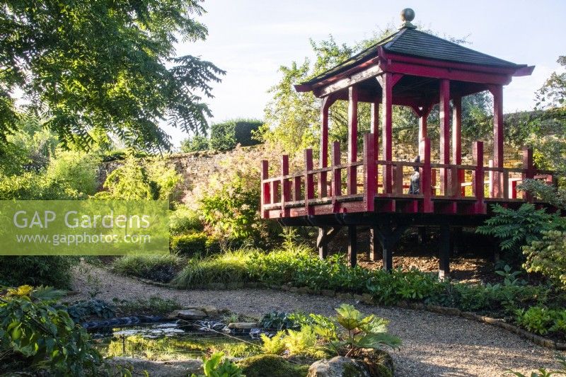 The wooden pagoda in The Thai Garden at The Manor, Little Compton, with a small pond in the foreground and planting that includes bamboo and hakonechloa.