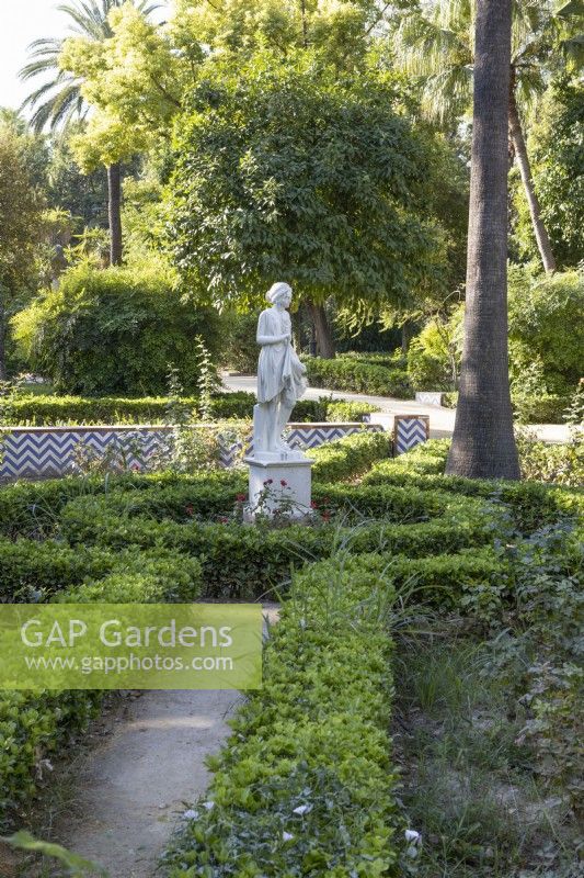 A figurative statue amongst clipped hedges. Parque de Maria Luisa, Seville, Spain. September