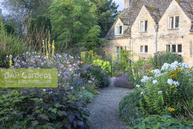 A gravel path winds through borders planted with perennials at The Manor, Little Compton.