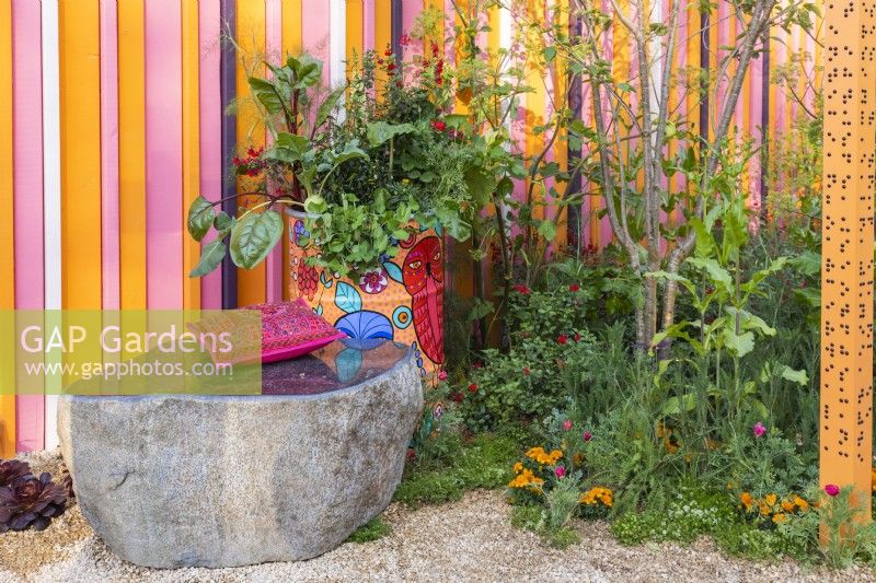 A stone bench, a painted old oil barrel planted with vegetables, herbs and flowers and perennial bed. The RHS and Eastern Eye Garden of Unity, Designer: Manoj Malde