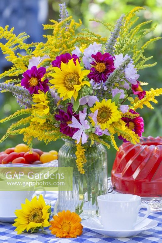 Summer bouquet with Sunflowers, Dahlia, Solidago, Agastache and Malva on the table set for a tea.