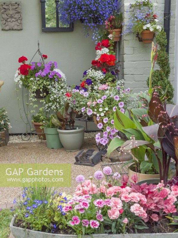 Cottage entrance with hanging baskets and containers of summer bedding plants