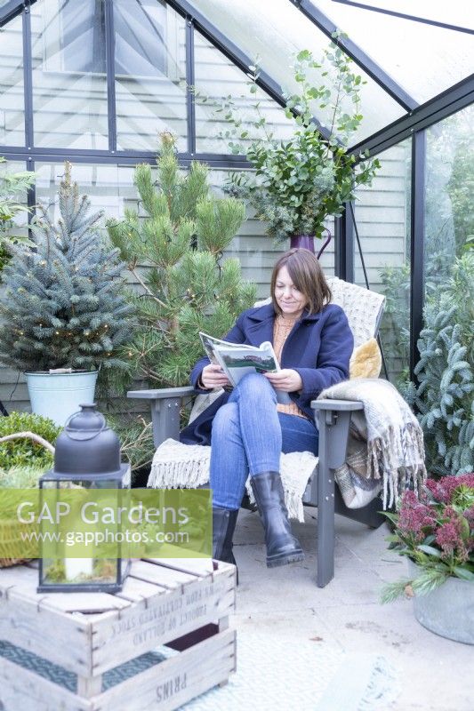 Woman reading magazine inside decorated greenhouse