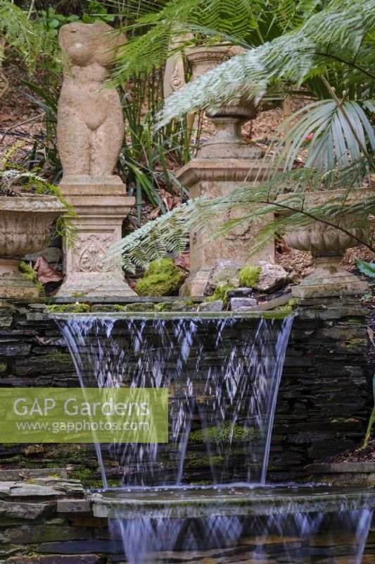 Stepped waterfalls in semi tropical garden with classical statues behind