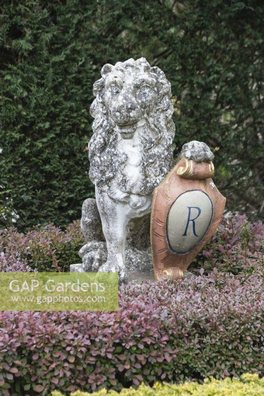 Stone lion sculpture with paw on shield with letter R on shield for Roy Strong. April. Spring.