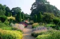 Formal rose garden with yew topiary and herbaceous borders at Mottisfont in Hampshire. 