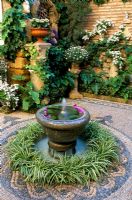 Fountain with circular planting and mosaics in courtyard garden , Cordoba in Spain