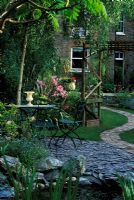 Small garden with slate chipping patio and curved path leading to house