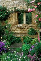 Window on old wall with climbing rose and stone bench at Broughton Castle in Banbury