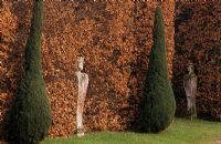 Fagus - Beech hedge with statues and clipped conifers at Chatsworth in Derbyshire