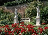 Rose garden with sculptures either side of bench at Polesden Lacey in Guildford, Surrey