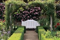 White bench in garden with box hedging and pergola at Mottisfont Abbey Gardens in Hampshire