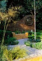 Arc Garden at Chelsea FS with woven fence, gravel, rustic wooden bench and grasses