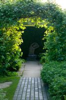 Archway of Sorbus aria 'Lutescens' with  statue 