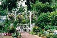 White painted gazebo with table and chairs. 