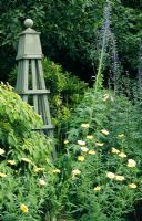 Green wooden obelisk in herbaceous border