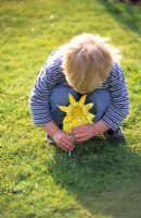 Child on lawn with cardboard daffodil