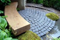 An oak bench and patio paved with cobble setts and water feature rill 
