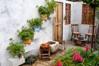 The 'Lebanese Courtyard' garden with geraniums in recycled tin cans and raised beds planted with herbs and fruit trees at The RHS Chelsea Flower Show.