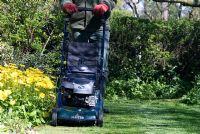 Man mowing the lawn with a petrol driven rotary mower in spring 