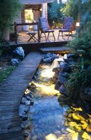 Decking with seating and pathway by lit pond