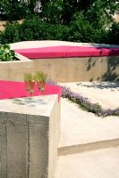 Modern seating with pink cushions in Abstracted Conglomerate garden Hampton Court FS

