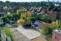 Roof garden with contemporary containers of grasses, decked area with table and chairs for entertaining - Plants creating screens