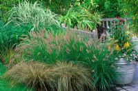 Carex flagellifera, Pennisetum orientale 'Karley Rose', Miscanthus sinensis 'Cosmopolitan' and Imperata cylindrica 'Rubra' in mixed border with container at New York Botanical Garden, USA