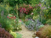 The gravel garden at Ketley's in high summer - Planting includes Malva sylvestris 'Primley Blue', Rosa 'Dorothy Perkins', Clematis 'Perle d'Azure', Stipa arundinacea, fennel and verbascums