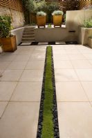 Modern garden with planted rill edged with polished black pebbles, designed by Charlotte Rowe
